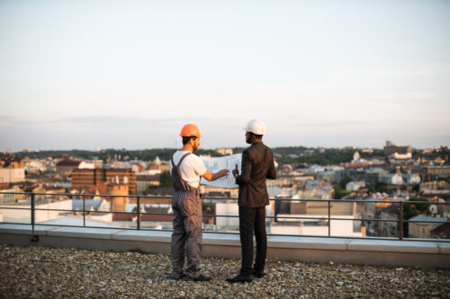 Commercial Roofing Experts on top of building looking at plan